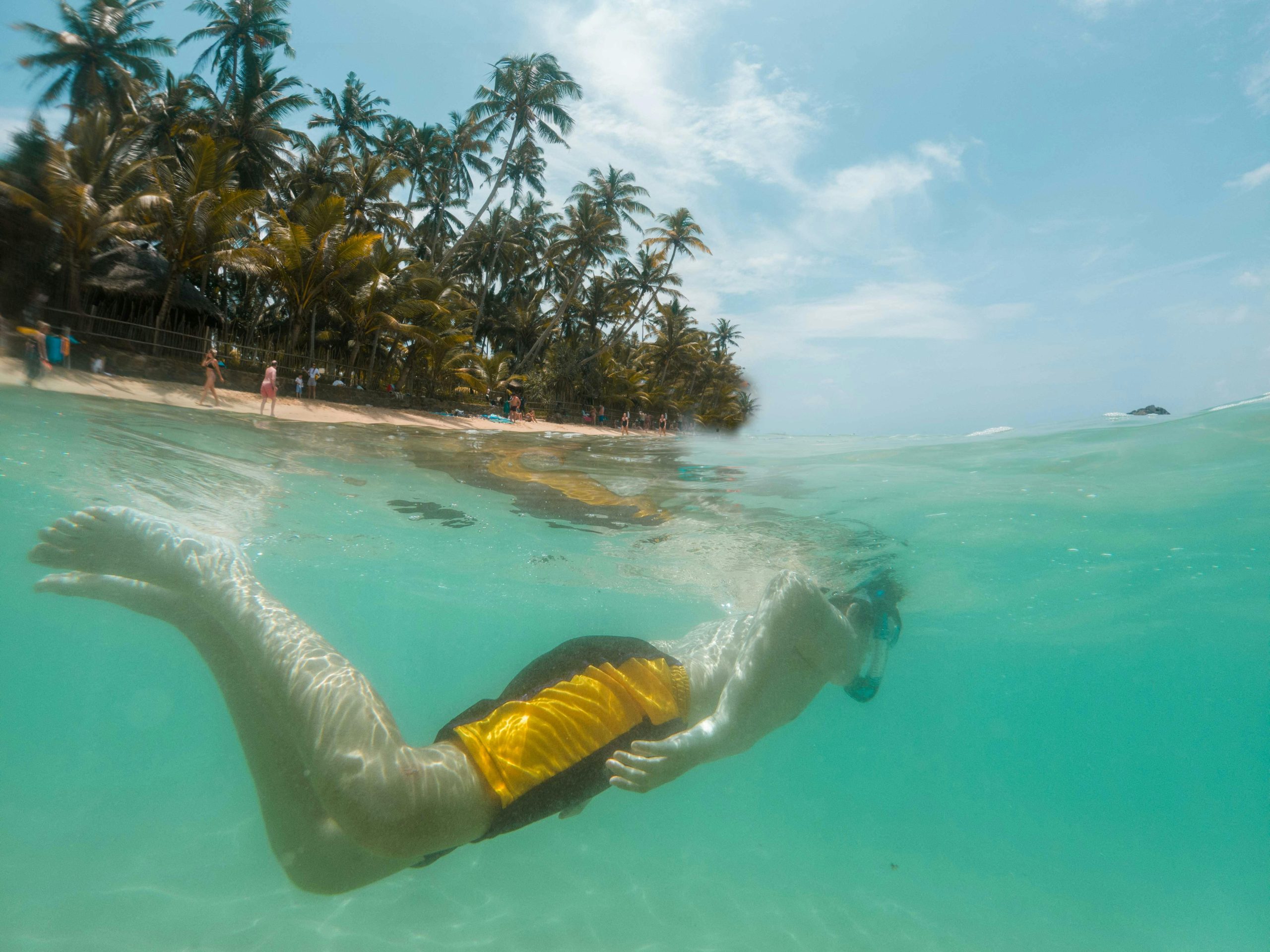 A teenager snorkeling in clear tropical waters near a palm-lined beach, capturing a vibrant summer vacation scene.