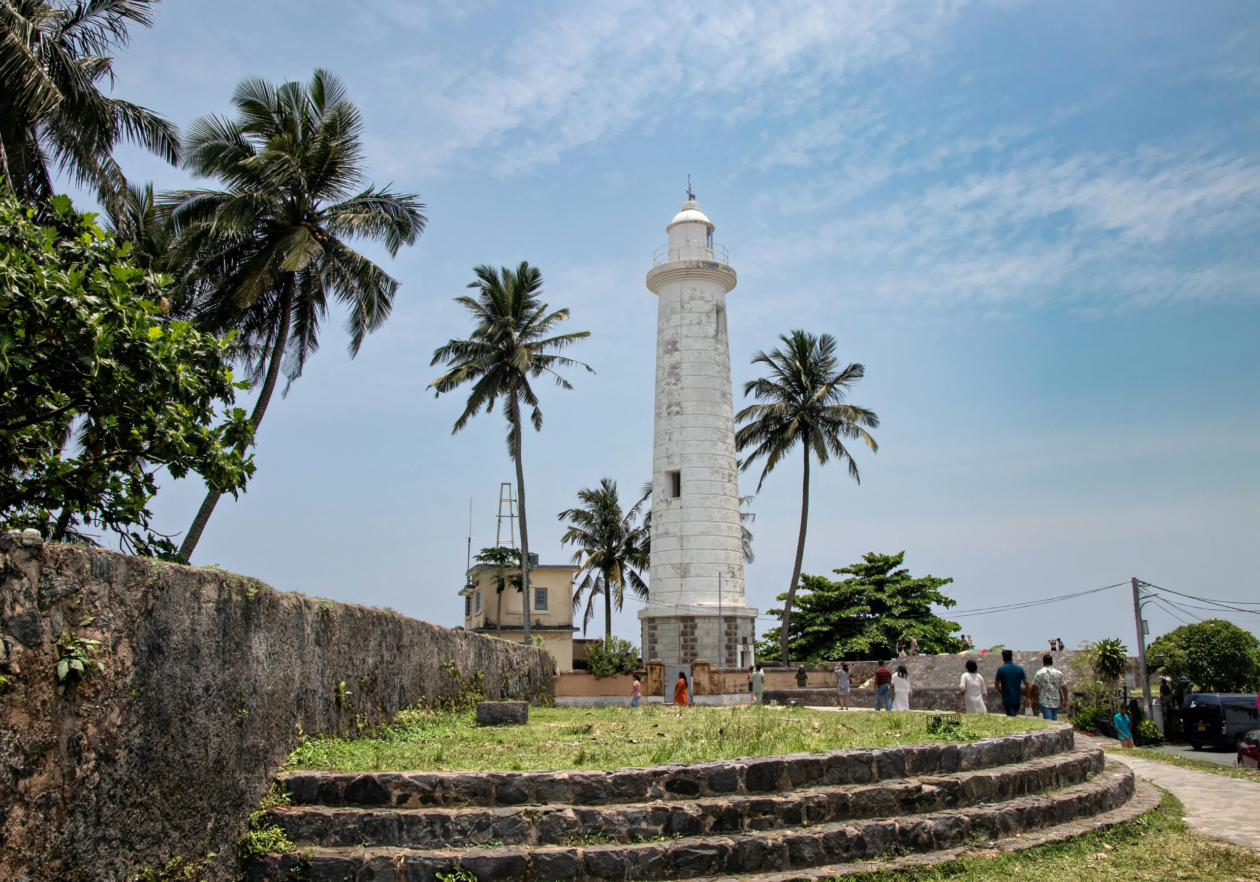 A picturesque view of Galle Lighthouse surrounded by palm trees in Sri Lanka's Galle Fort.